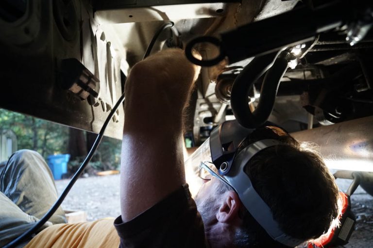 Cutting tabs off the Delica Colin is cutting brackets and tabs off so that the aluminum box will fit in the space under the van that used to house the rear heater core and AC.