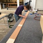 Lucia prepping each piece with wood glue after the dry fit is successful. Wood ceiling installation for Mitsubishi Delica L300